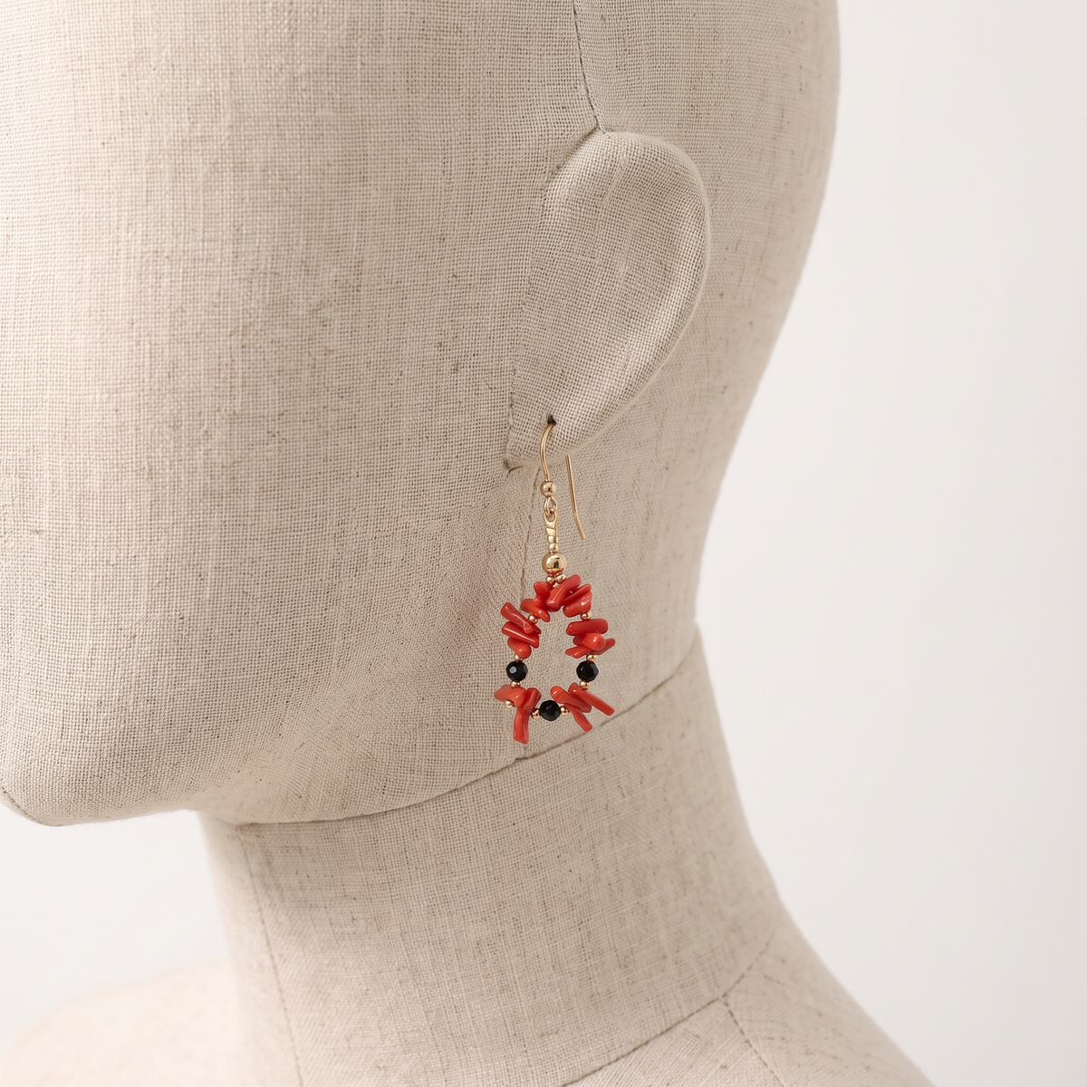 NOÉMIE — boucles d'oreilles en corail présentées sur une oreille en lin