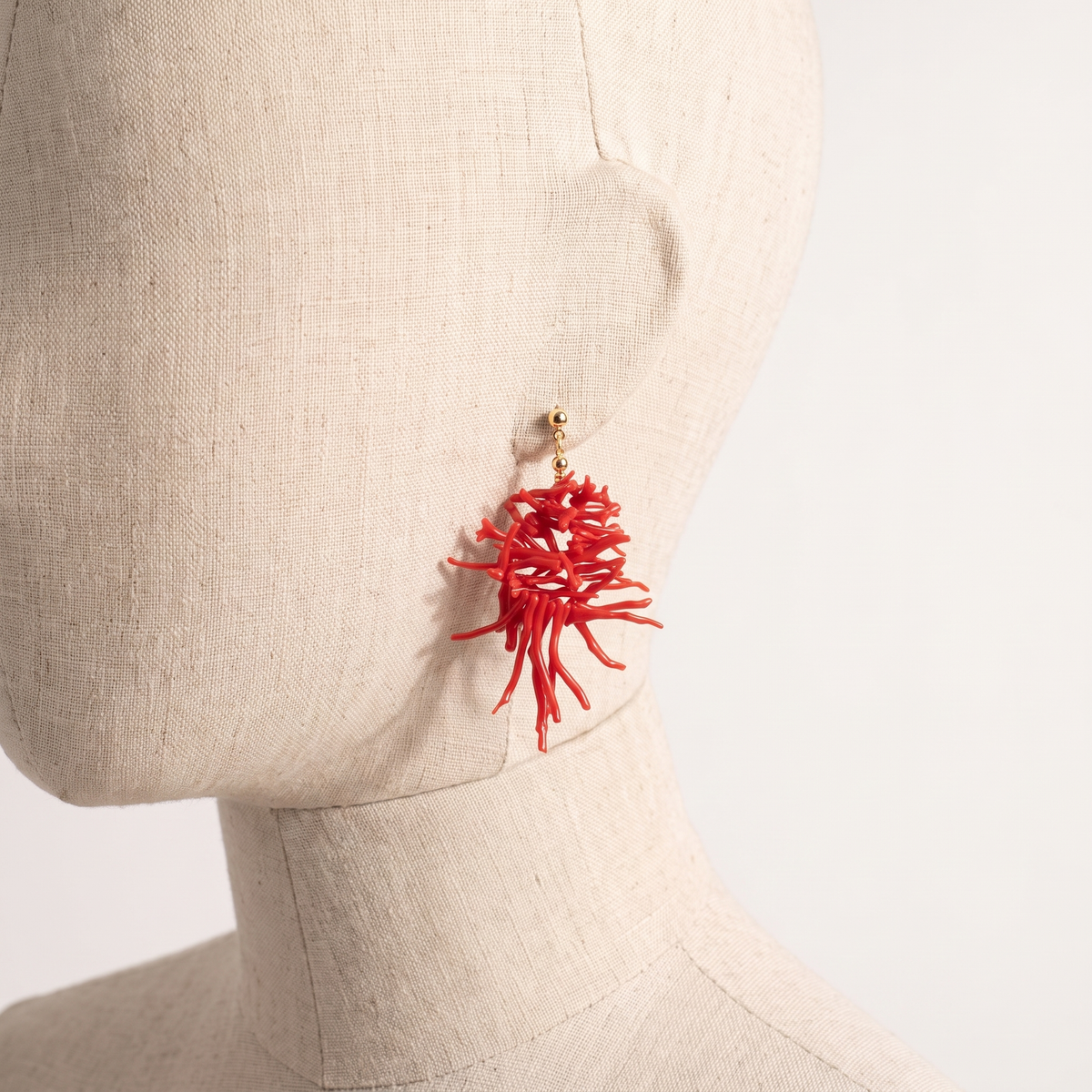 AURORE — boucles d'oreilles en corail présentées sur une oreille en lin