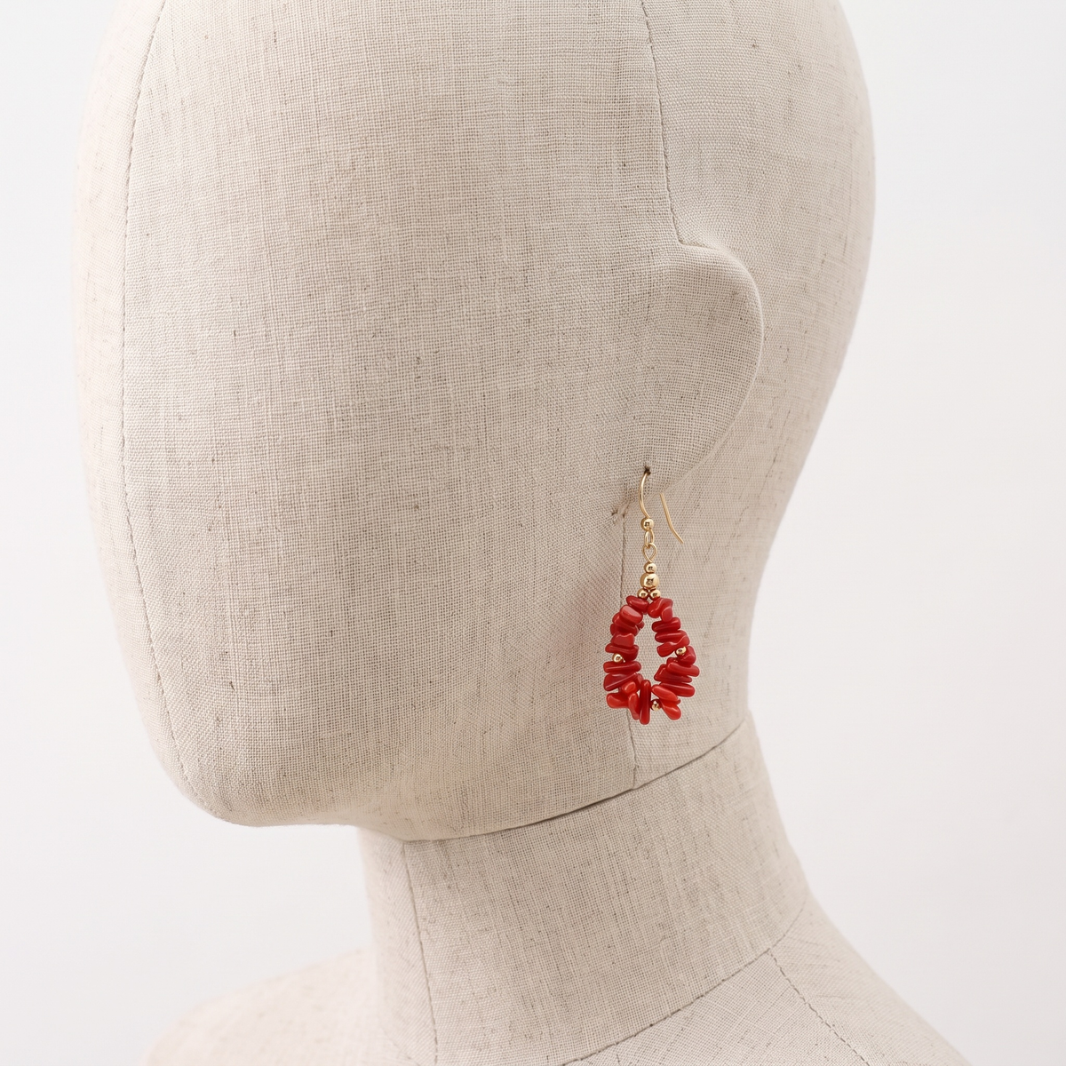 MARIS — boucles d'oreilles en corail présentées sur une oreille en lin