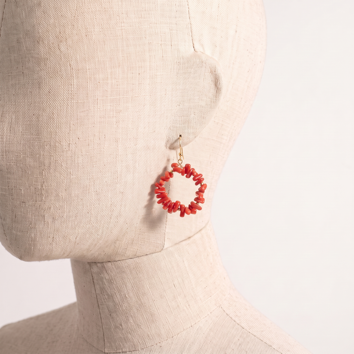 NIXA — boucles d'oreilles en corail présentées sur une oreille en lin