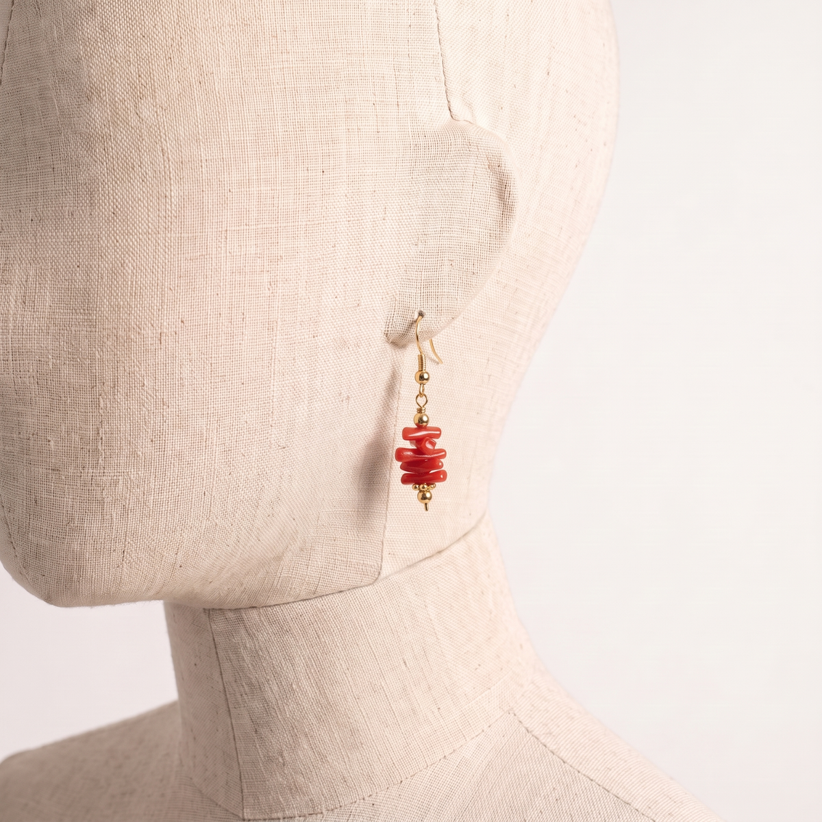 SYRA — boucles d'oreilles en corail présentées sur une oreille en lin