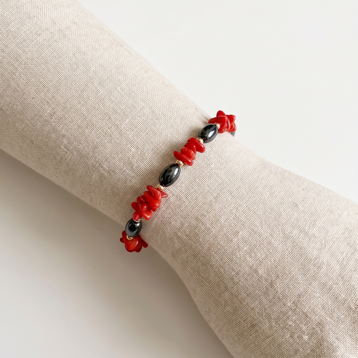 NYX — bracelet en corail sur un présentoir poignet en lin