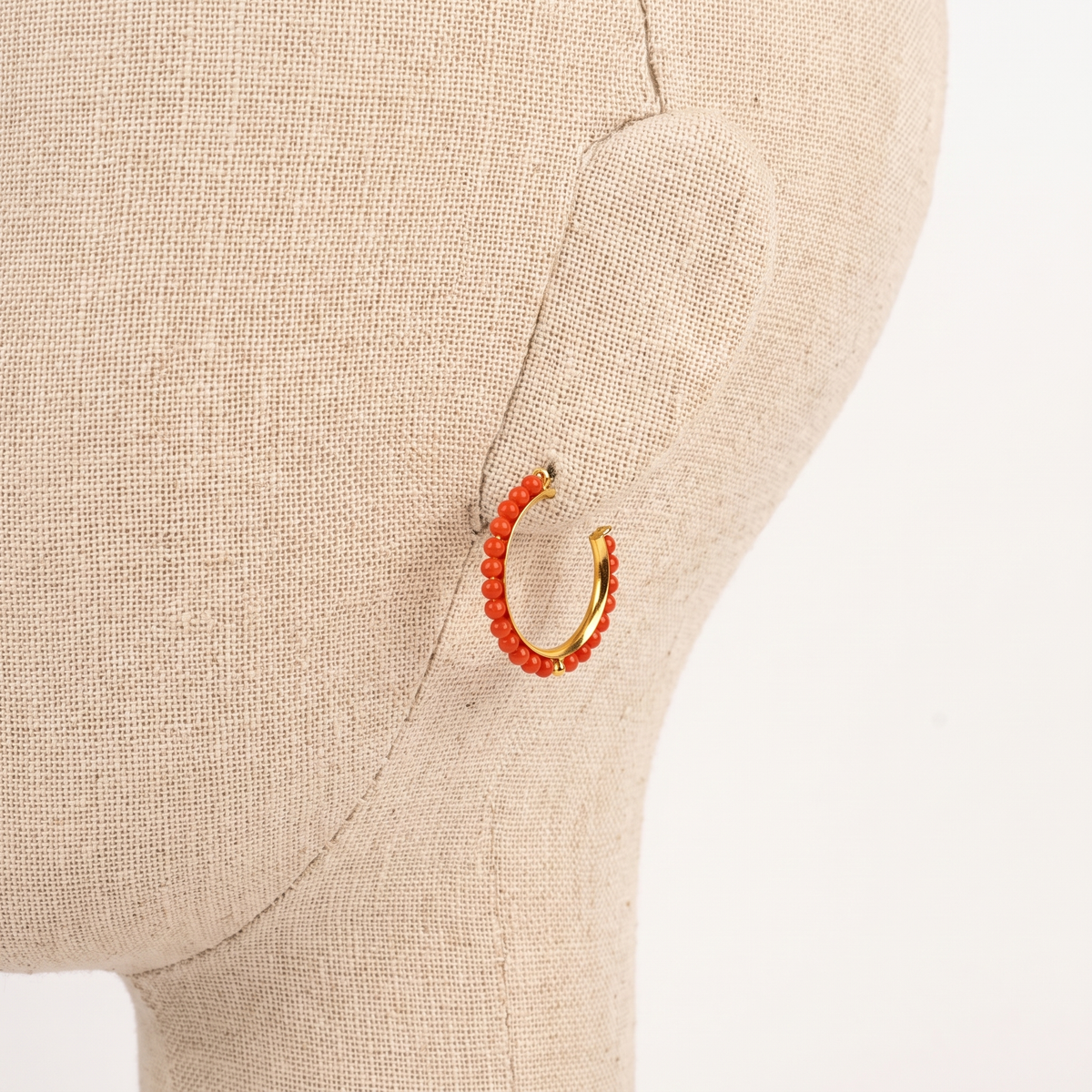 ALEKSANDRA — boucles d'oreilles en corail présentées sur une oreille en lin